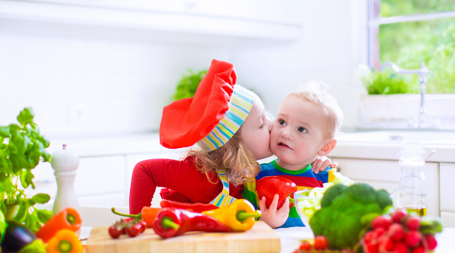 キッチンにいる幼い兄弟、1歳の弟の
頬にキスする2歳の姉